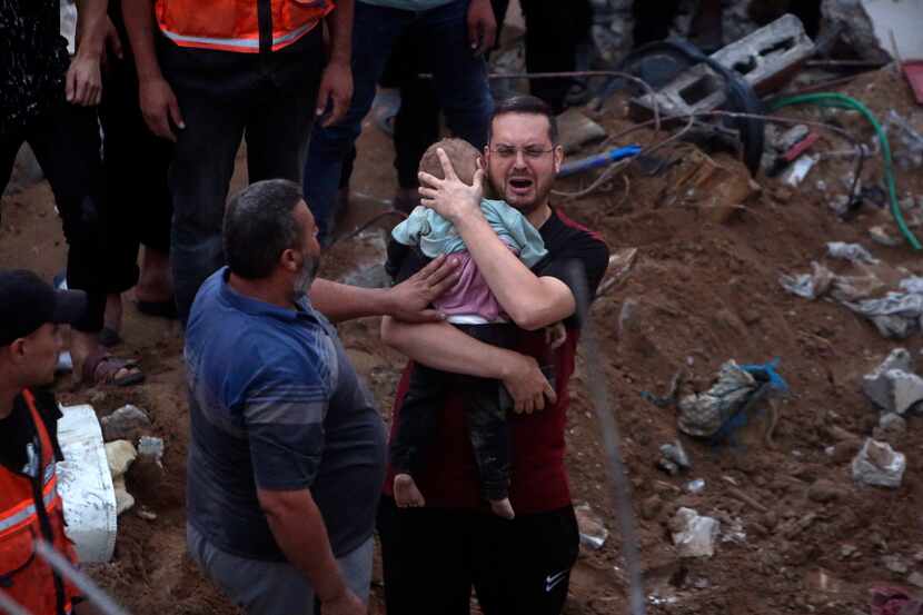 A Palestinian man cries while holding a dead child found under the rubble of a destroyed...