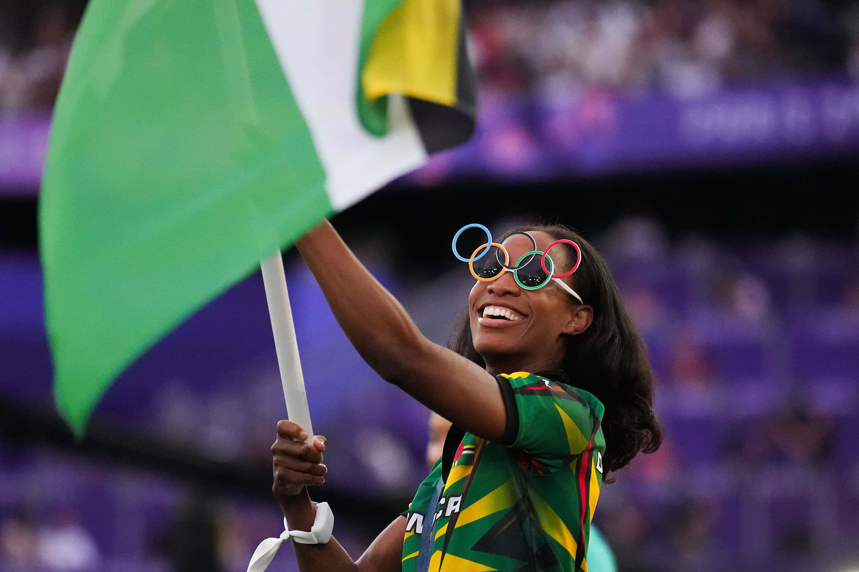 Thea LaFond of Dominica wears Olympic ring glasses as she carries her country’s flag into...