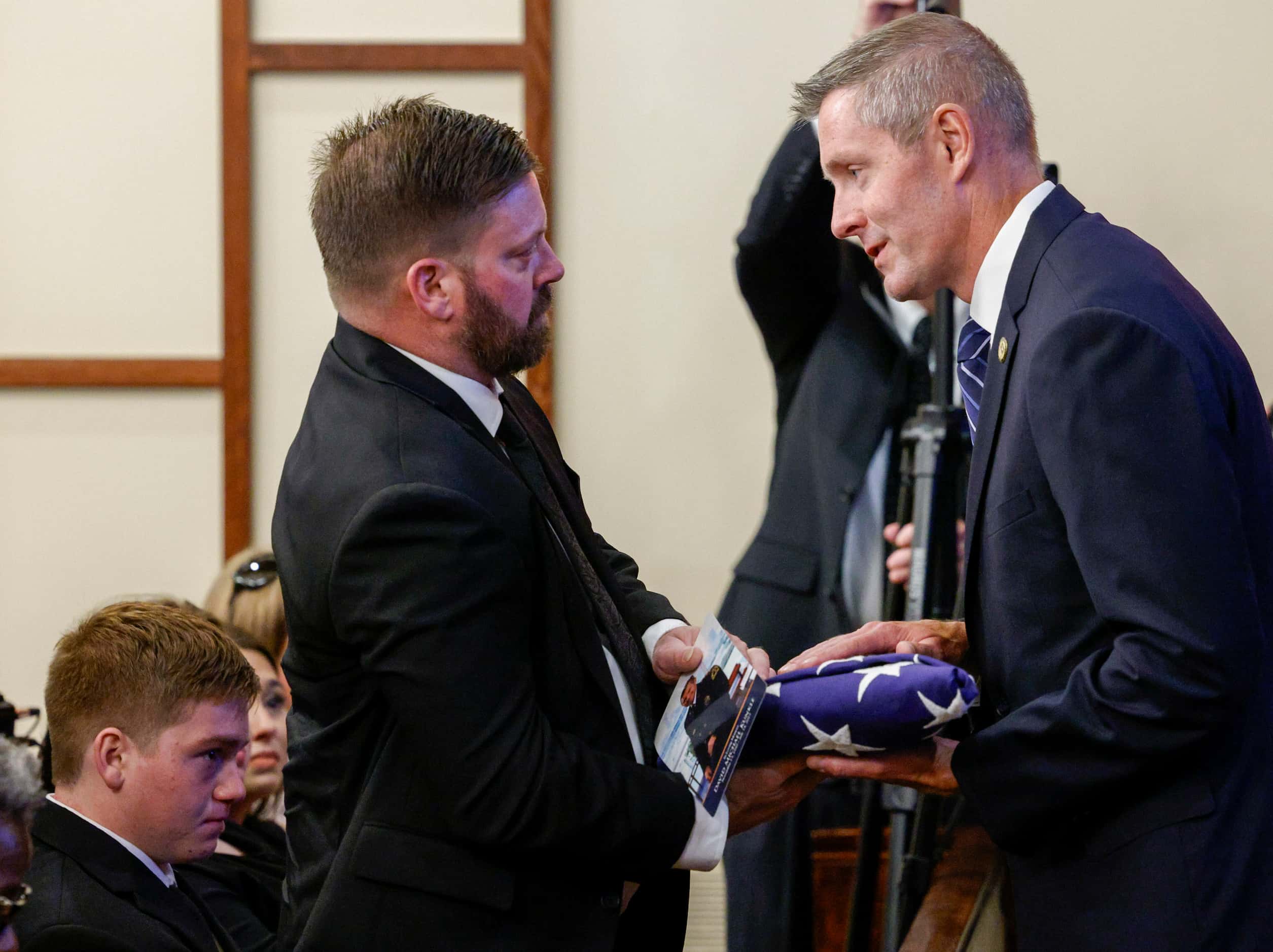 Dallas City Council member Chad West (right) presents a flag to David Kunkle’s son Michael...
