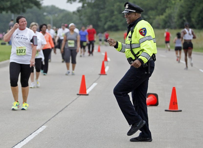 Arthur Parker, the school resource officer at Clark High School in Plano, entertains runners...