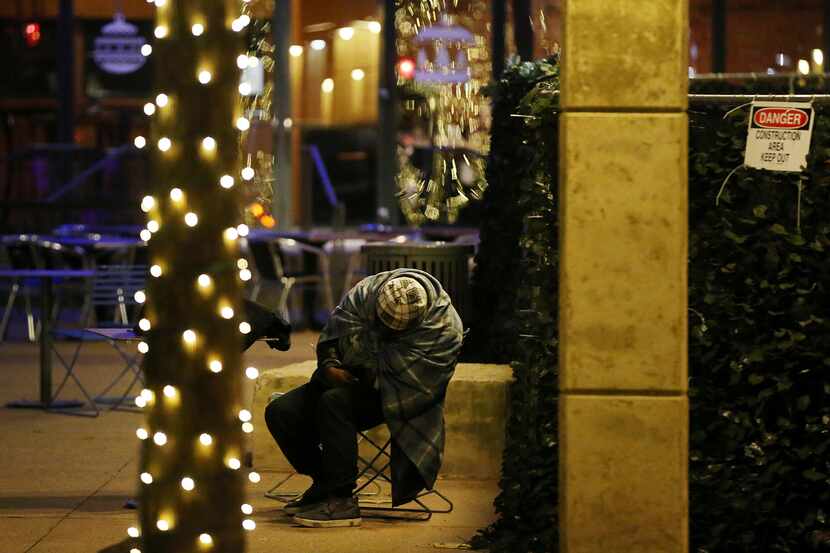 A homeless person slumps over in a chair in Pegasus Plaza in downtown Dallas on New Years...