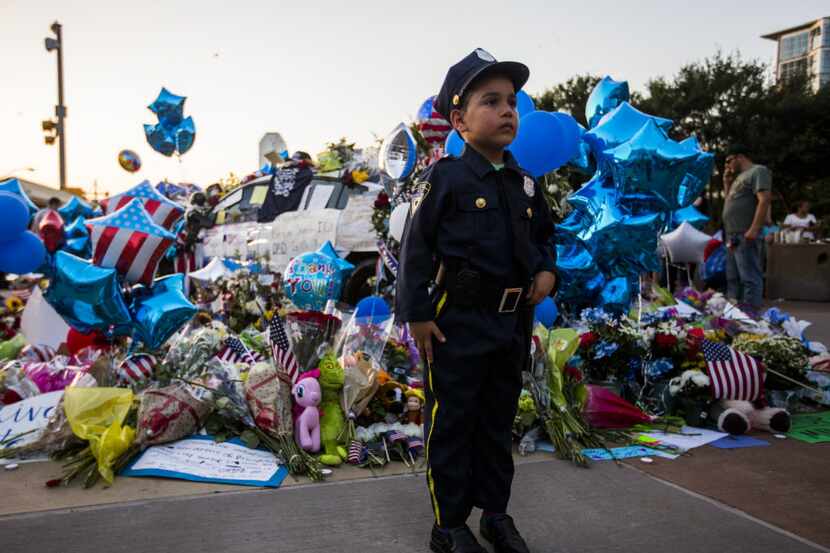 Diego Diaz, 6, stands at attention dressed in a police officer costume next to a memorial...
