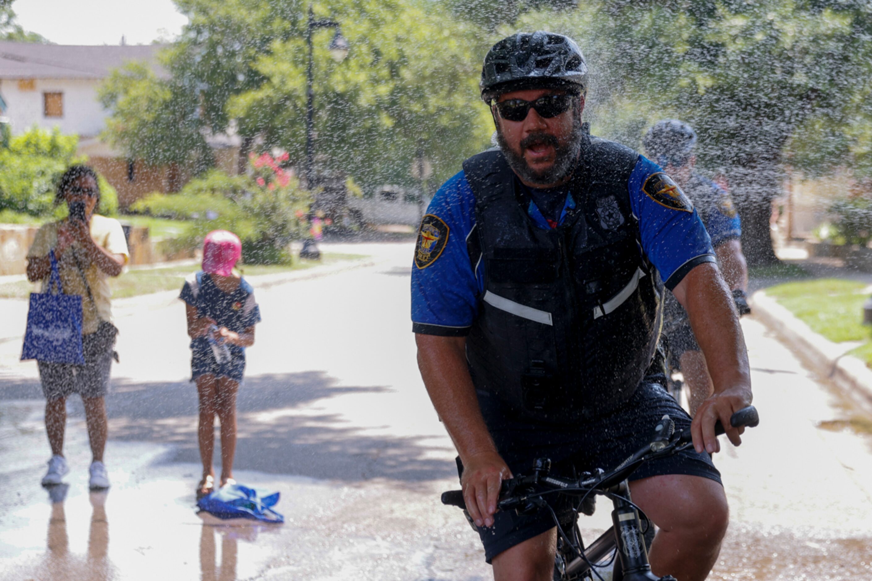 Fort Worth Police Department officers cool off as they pass along a hose of water during...