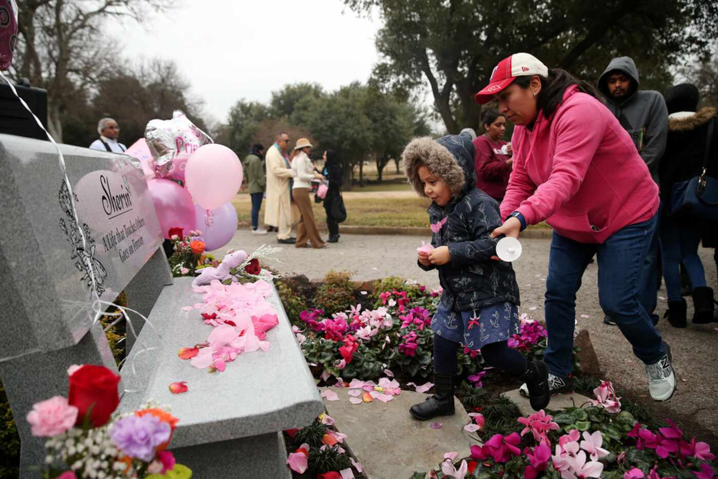 Lorena Gonzales of Richardson led her daughter Eva Gonzales to leave petals at a bench...