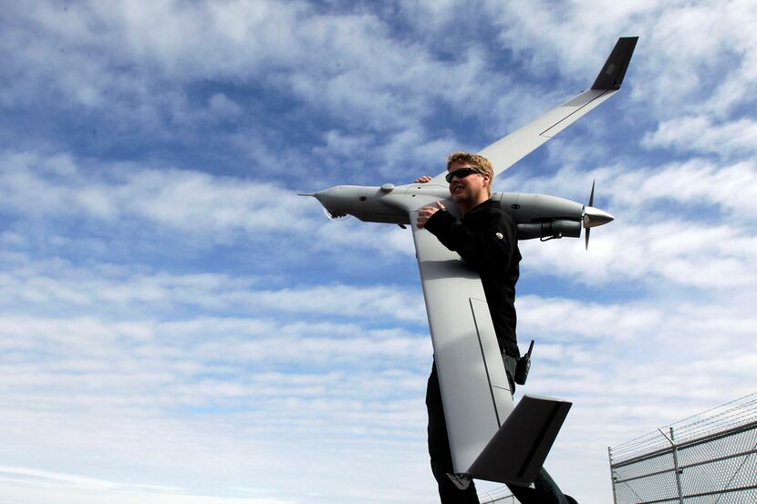 Flight test pilot Alex Gustafson carries an InsituScanEagle drone aircraft in preparation...