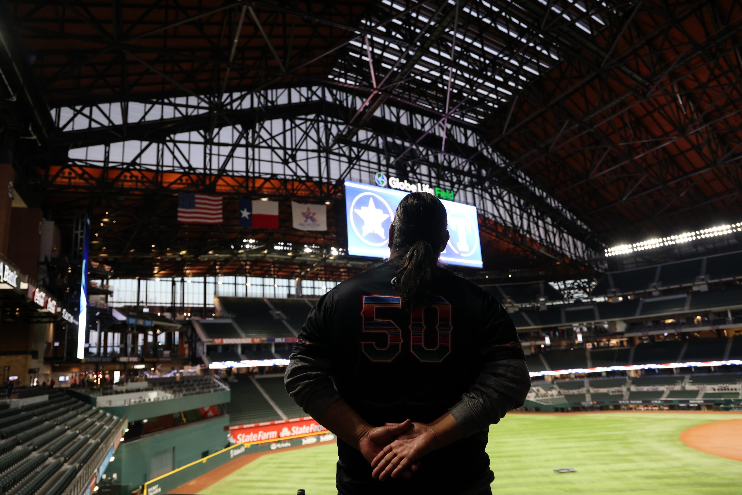 A Texas Rangers fan stands for the playing of the national anthem before game one of the...