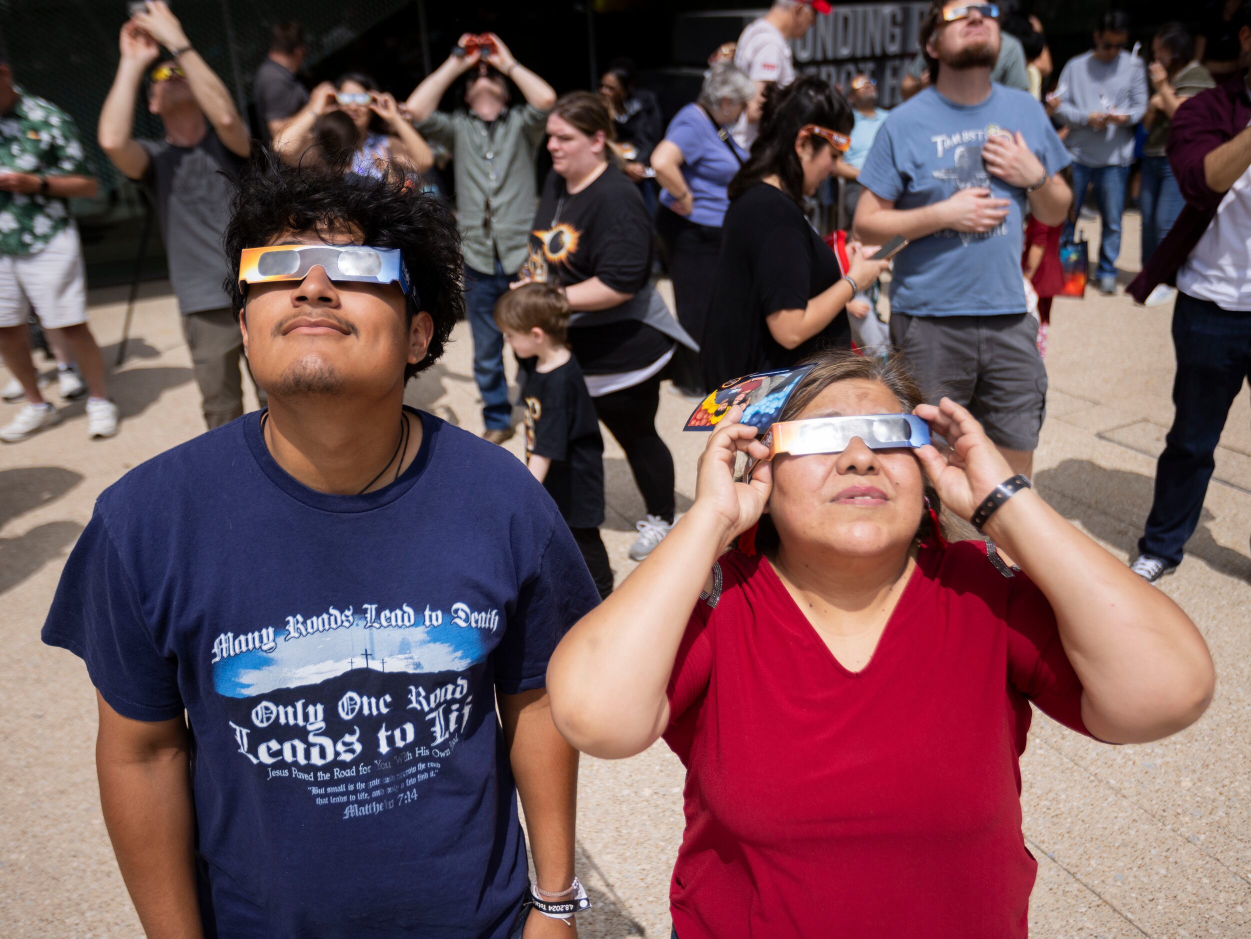 (From left) Eduardo Cervantes, 17, of Arlington, TX watches the eclipse with mom Sara...