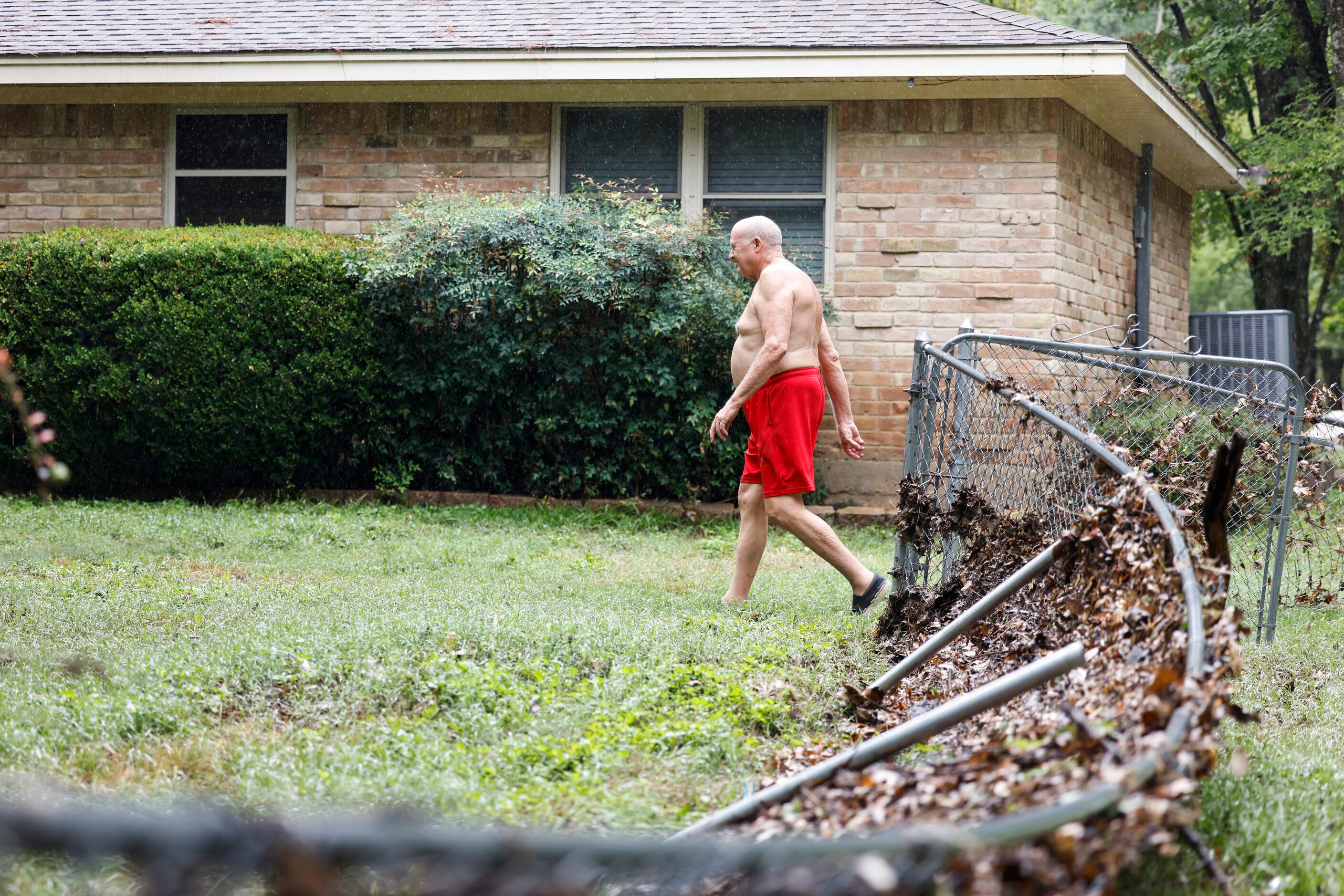 Home owner, Garry McDaniel walks by the damaged fence of his house in Balch Springs, a day...