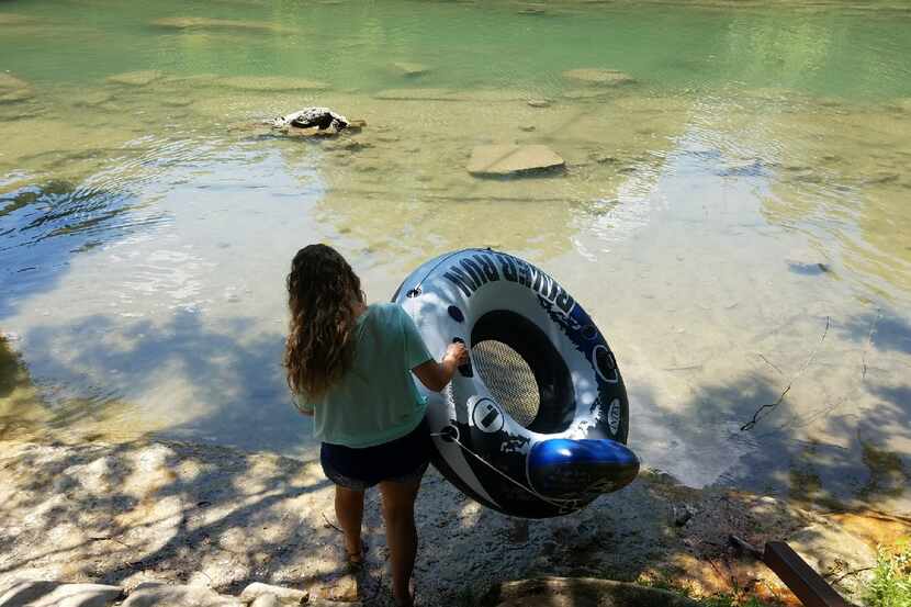 Tracy Corum of Bellville carries a river tube into a quiet spot on the Guadalupe River near...