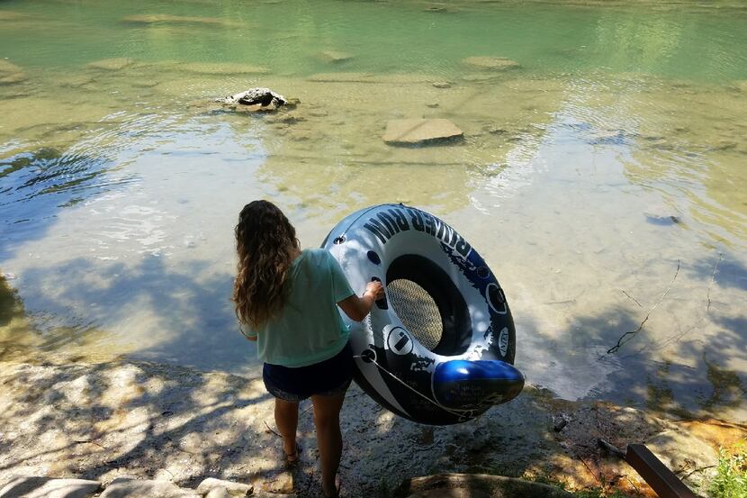 Tracy Corum of Bellville carries a river tube into a quiet spot on the Guadalupe River near...