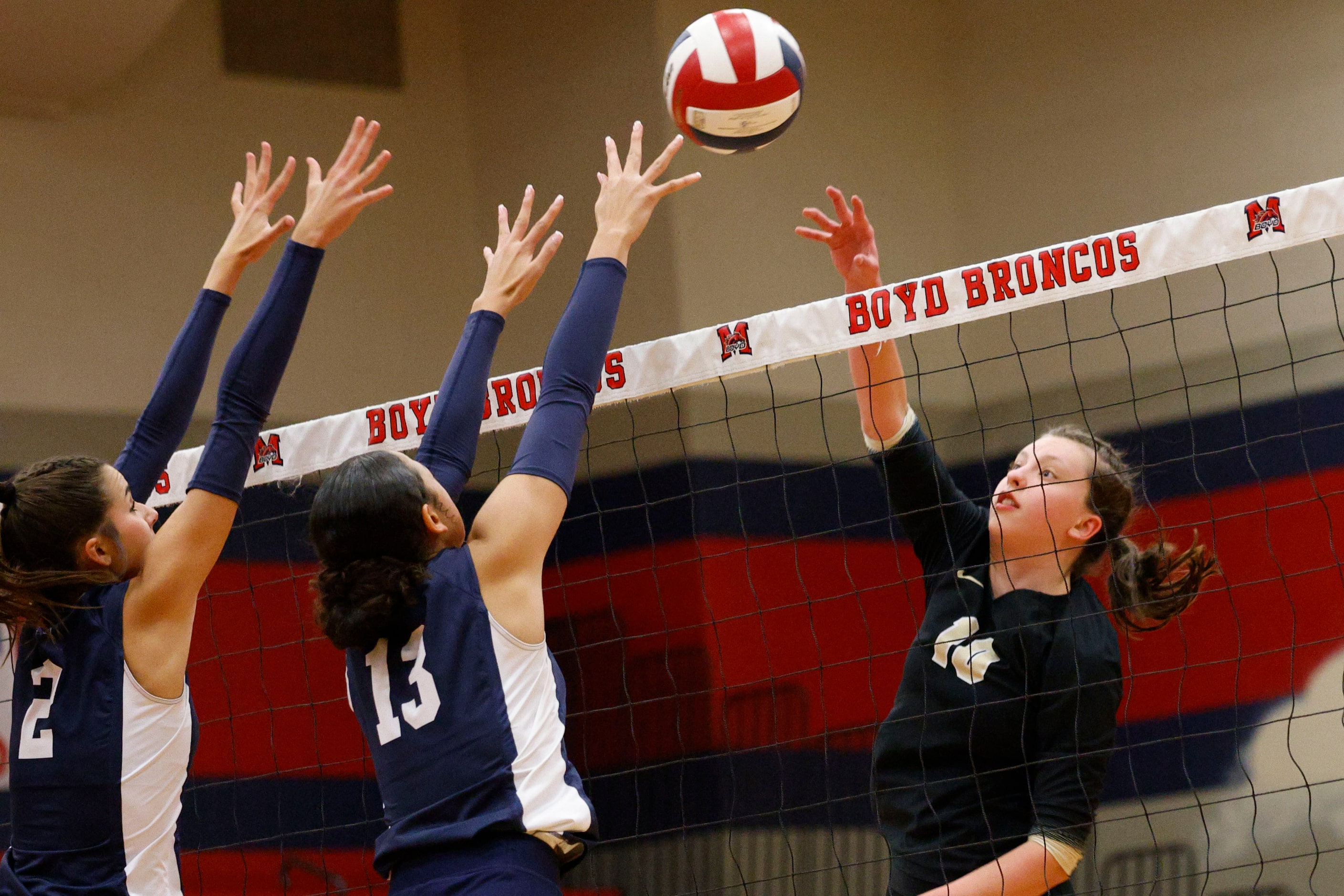 Plano East's Elena Davenport (10) spikes the ball against McKinney Boyd's Keira Bose (2) and...