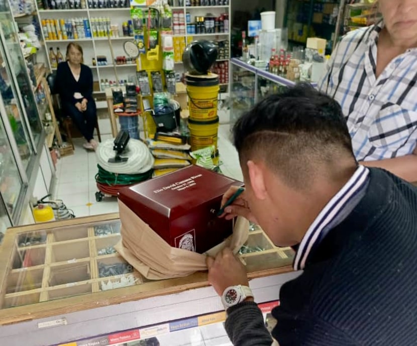 A man tries to open the urn with the ashes of Elio Cumana in a store in Bogotá, Colombia....