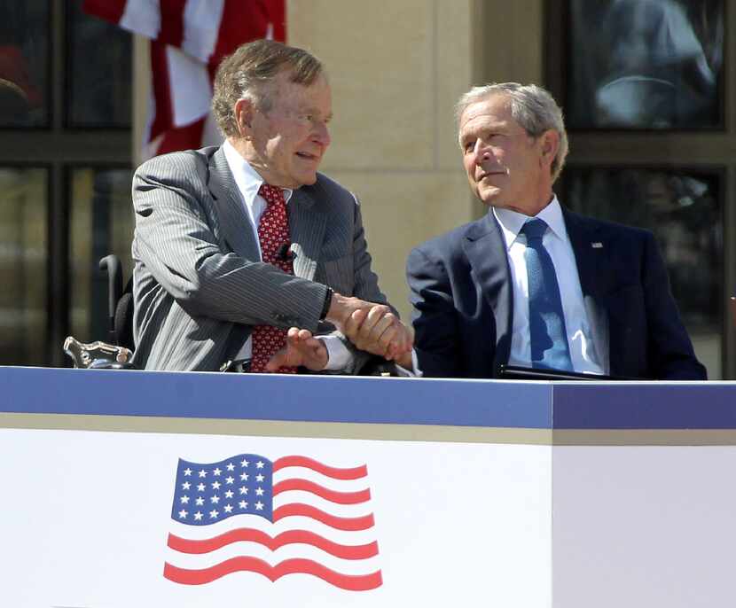 In this 2013 file photo, former President George W. Bush shakes hands with his father,...