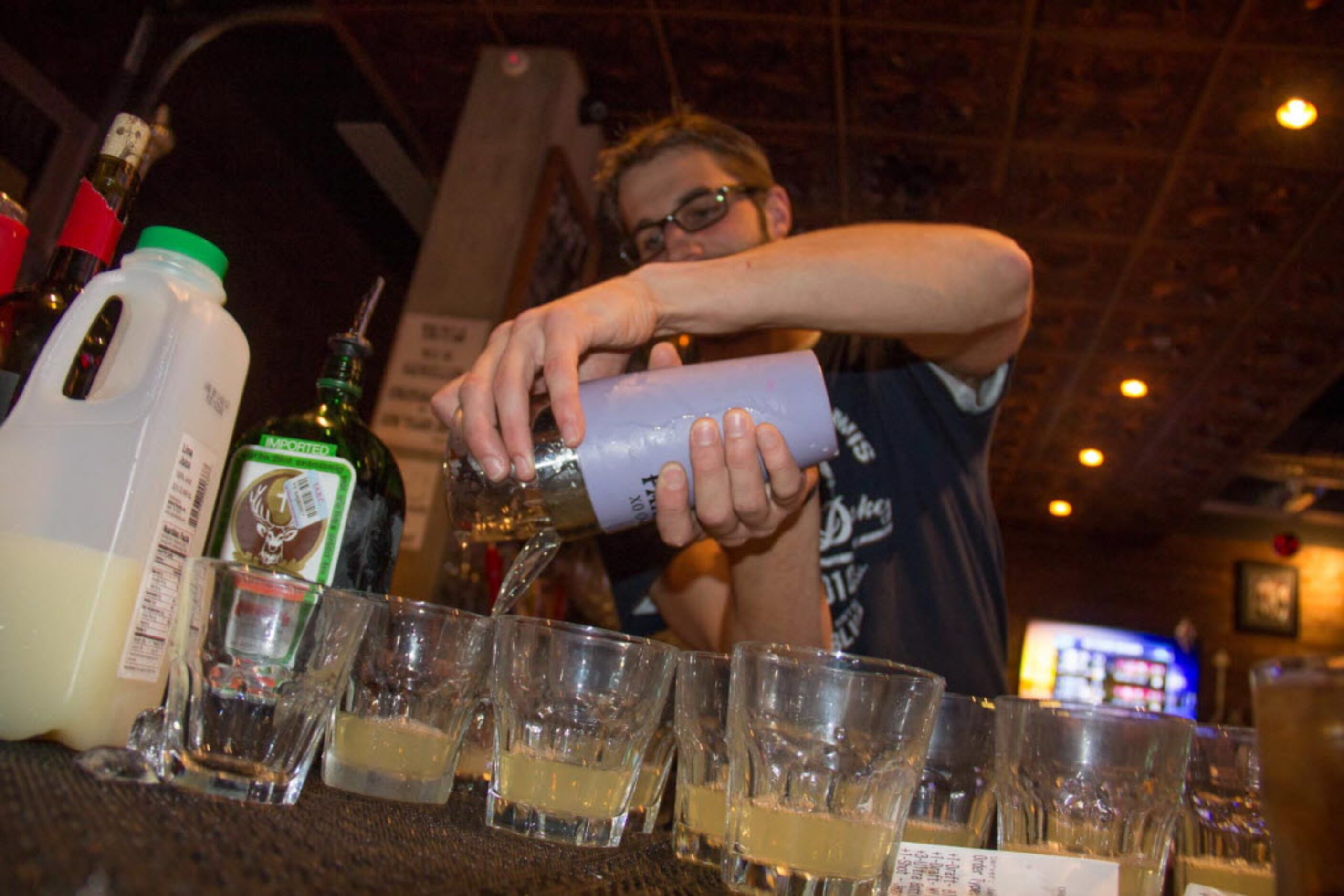 Bartender Sage Bueltel mixes up some shots for the patrons at the Cowboy watching party at...