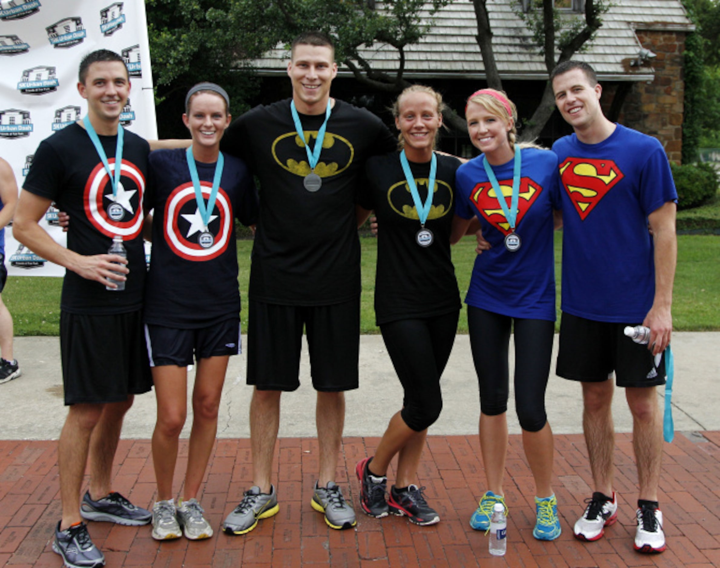 A group of runners pose for photos after crossing the finish line during the Second Annual ...