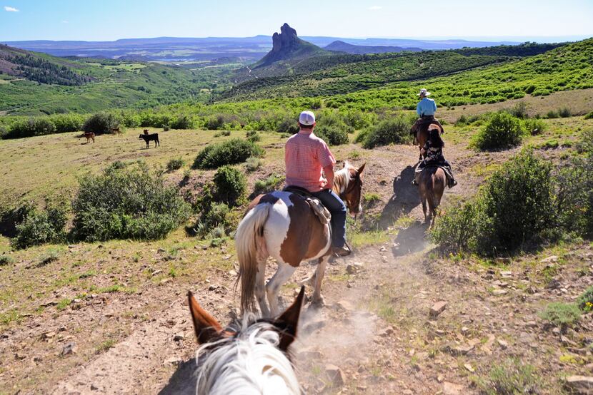 Guests ride on a trail at Smith Fork Ranch with the unique Needle Rock in the background. 