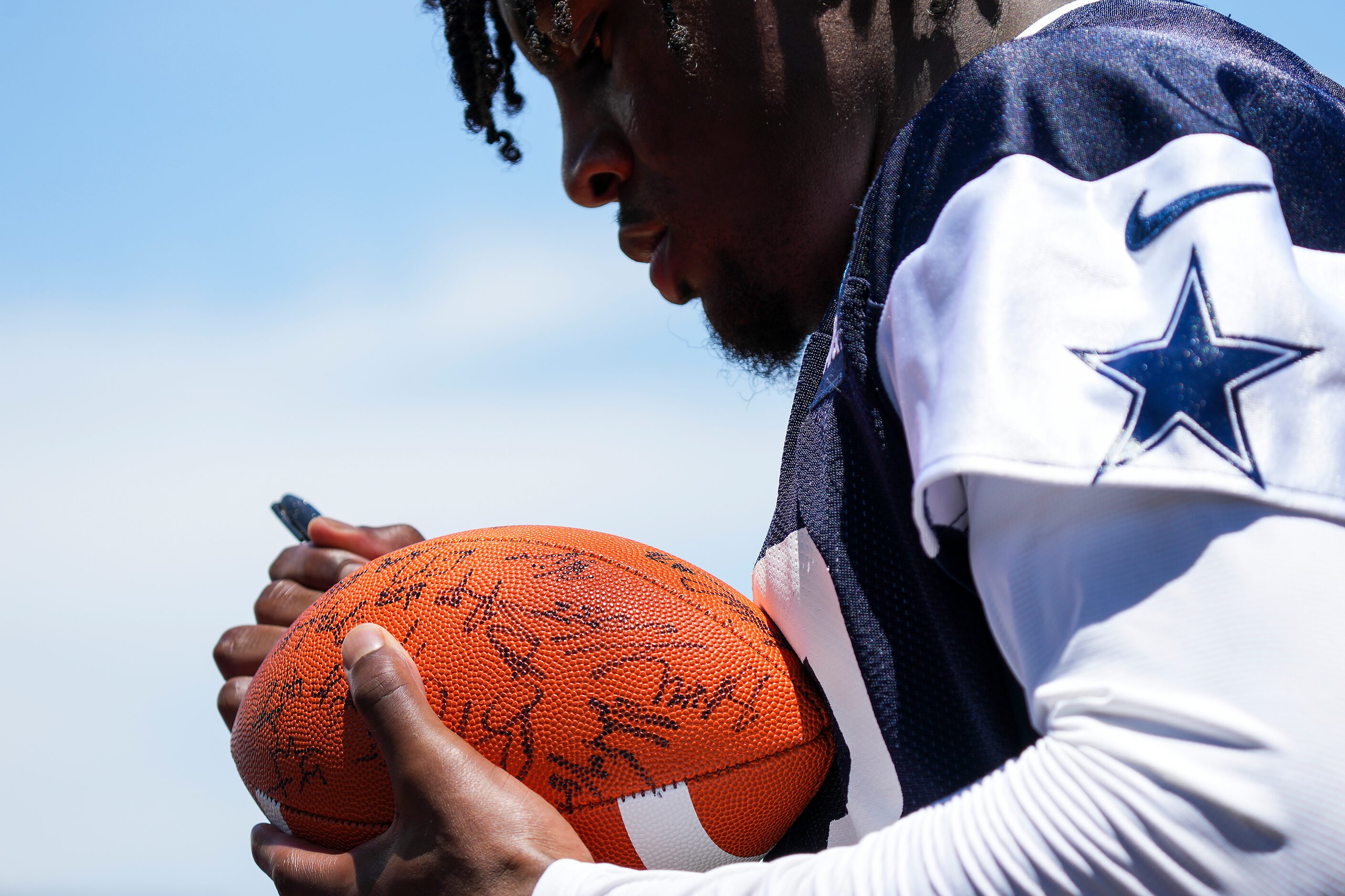 Dallas Cowboys linebacker Damone Clark autographs a football following the first practice of...