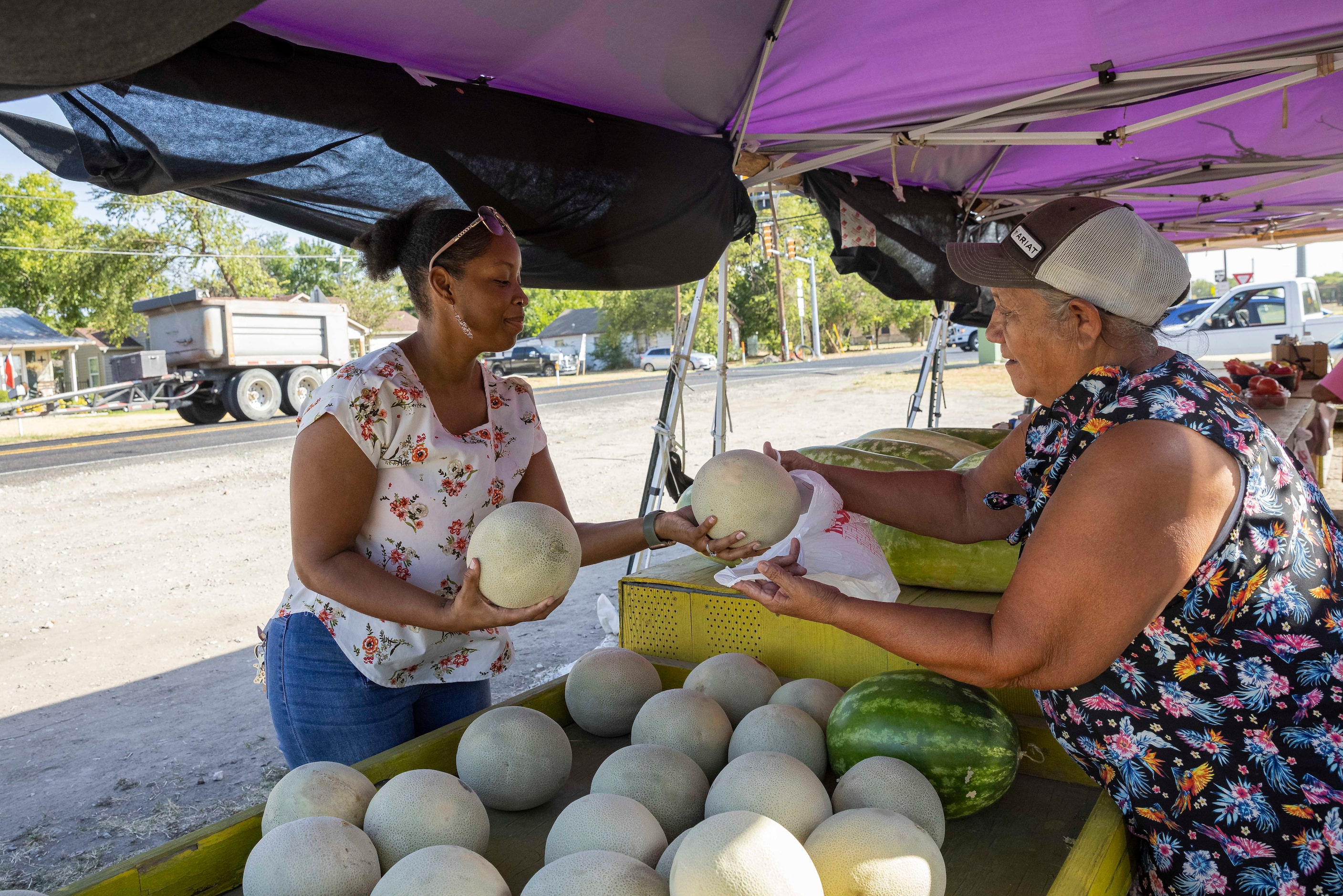 Kiarra Settles-Washington (left) of Royse City buys melons from Lupe Castillo on Aug. 17,...