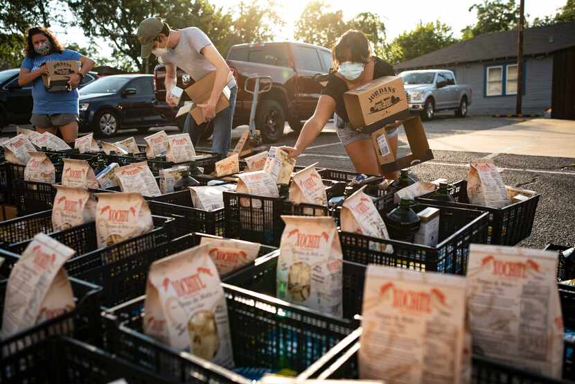 Jackie Vasquez (der.) una voluntaria ayuda a empacar cajas durante una entrega de comida...