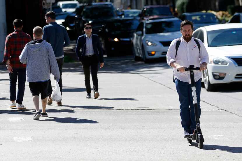 A man rides a Bird electric scooter in Uptown on Tuesday.
