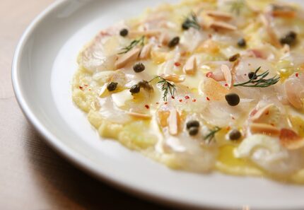 Bronzino crudo skordalia with potato skordalia, almonds, celery, crispy potato and dill at...