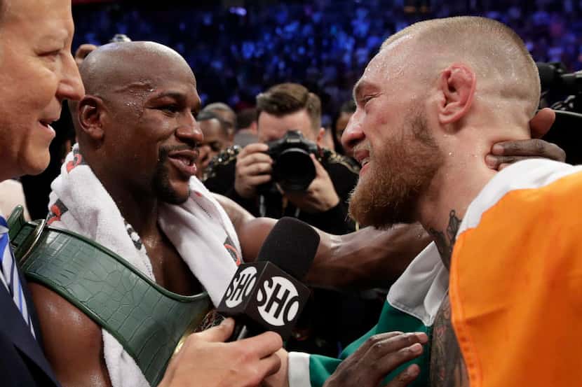 Floyd Mayweather Jr., left, speaks with Conor McGregor after a super welterweight boxing...
