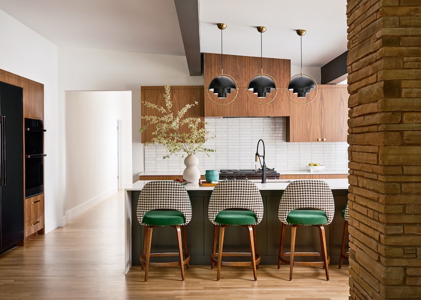 A kitchen features walnut cabinetry, a large island with barstools, and ceramic vases.