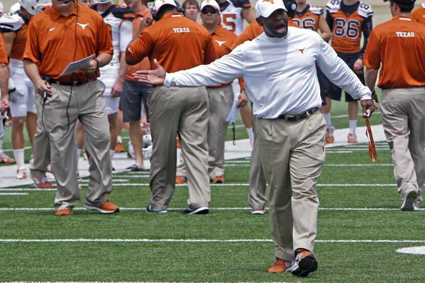 Texas coach Charlie Strong looks for a high five from his players during the first half of...