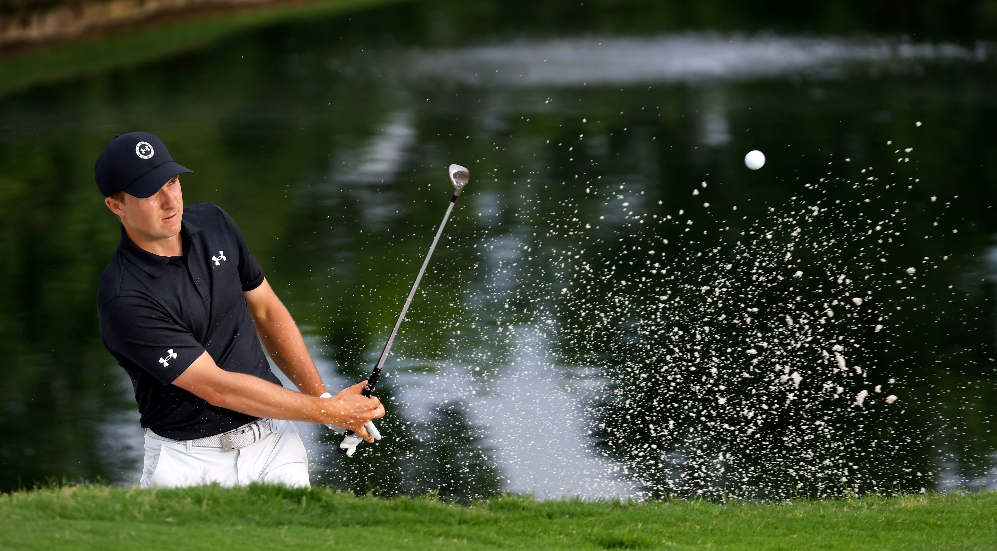 Professional golfer Jordan Spieth hits out of the green side bunker on the par-3, No. 16...