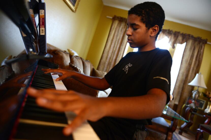 Roman Scott, 11, plays the Chariots of Fire theme song on the piano at his home in Cedar...