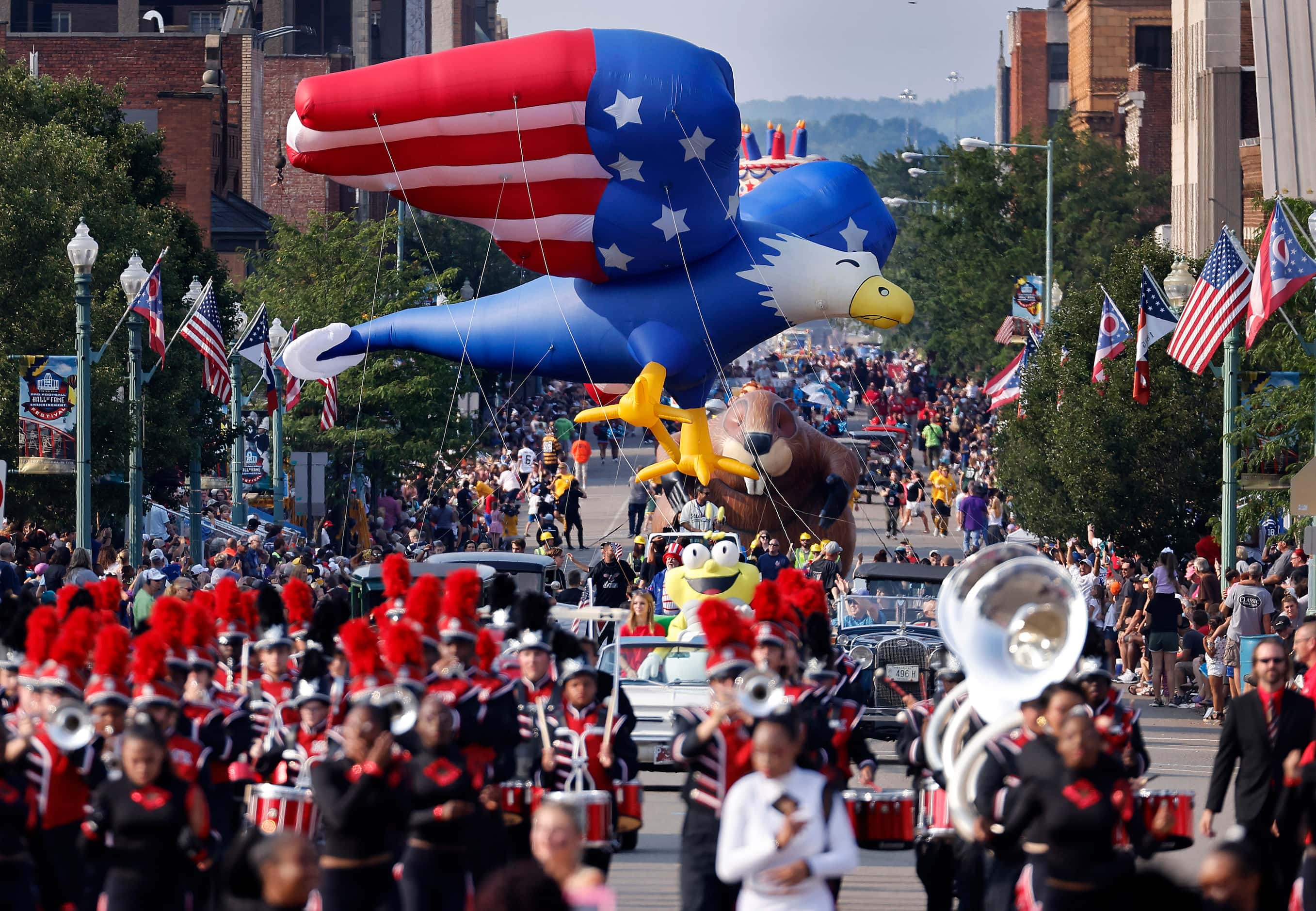 Large inflatable floats combined with marching bands and classic cars carrying Pro Football...