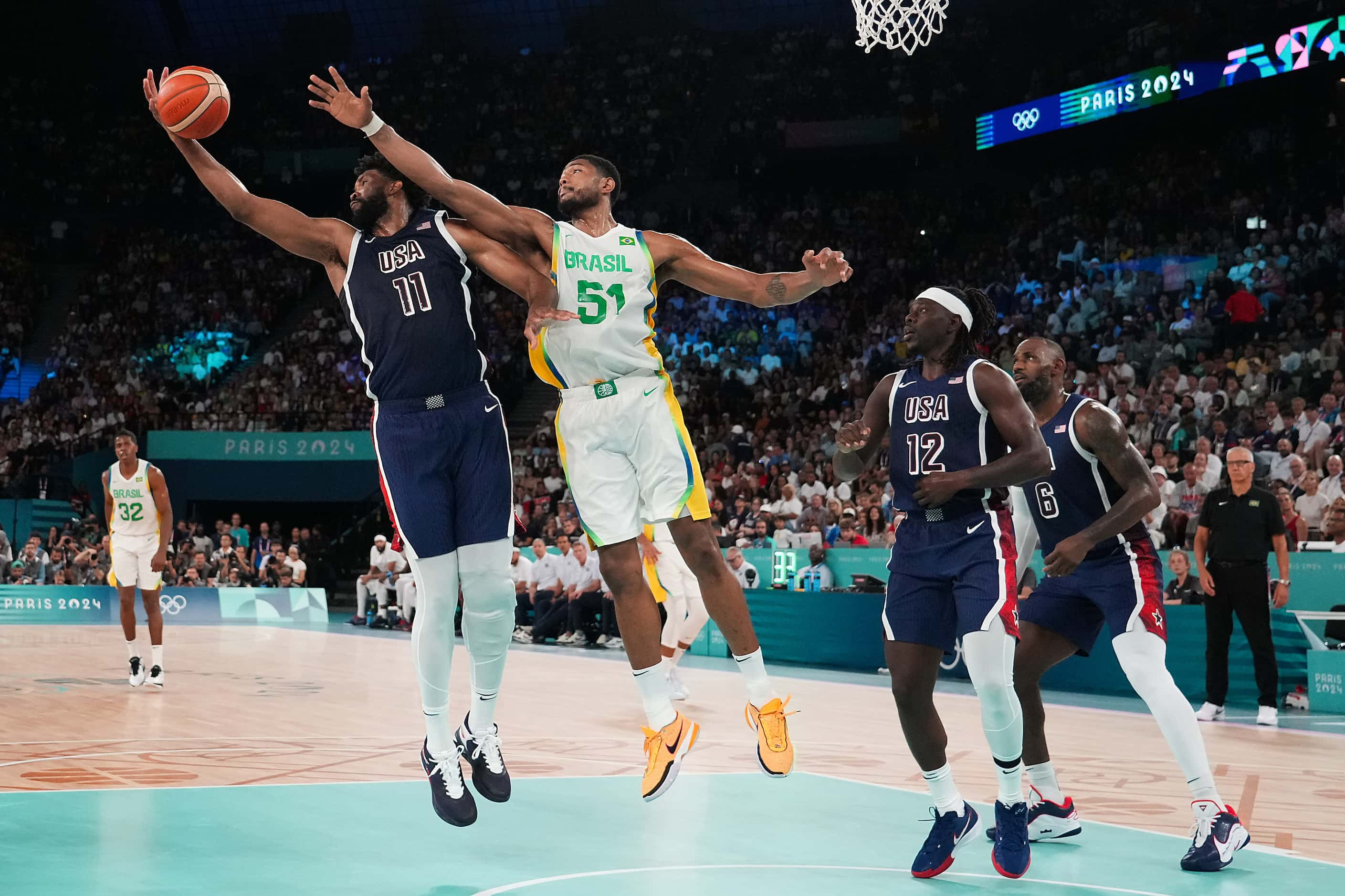 Joel Embiid (11) of the United States grabs a rebound away from Bruno Caboclo (51) of Brazil...