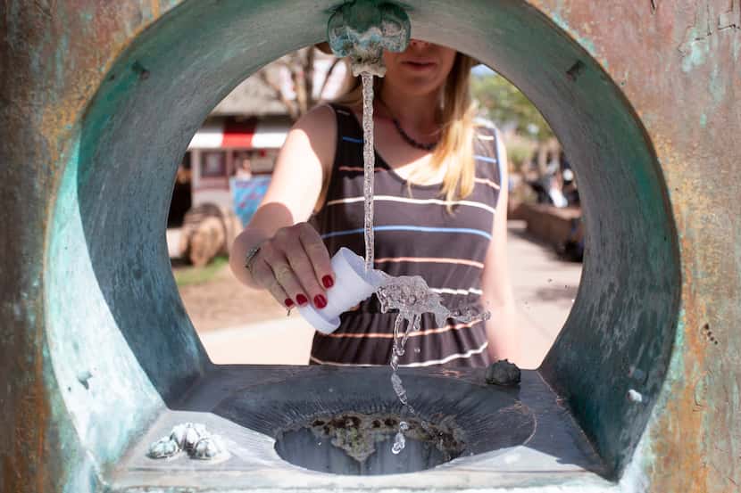 A woman samples the water from one of the eight mineral springs that feed into Manitou...