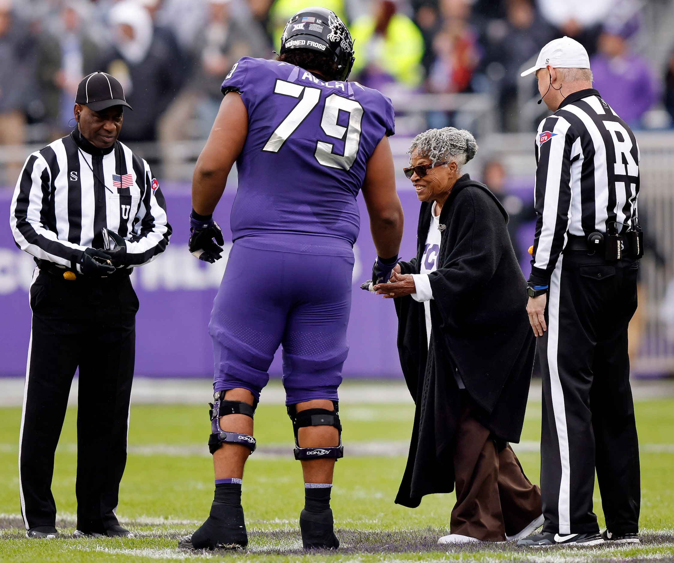 TCU Horned Frogs center Steve Avila (79) helps Grandmother of Juneteenth, Opal Lee, off the...