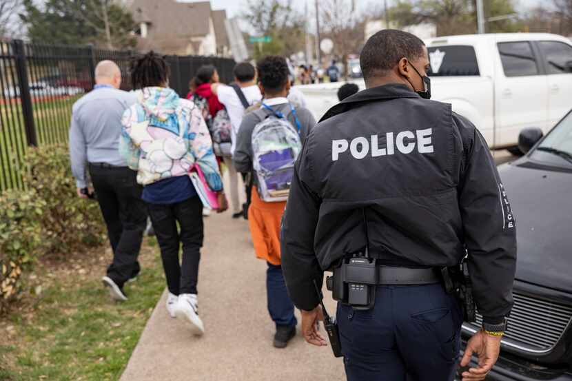DISD police officer Douglas walks behind students from J. L. Long Middle School as they walk...