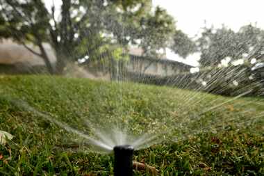 Sprinklers water the lawn in front of a house in the 3700 block of Beverly Drive in Highland...