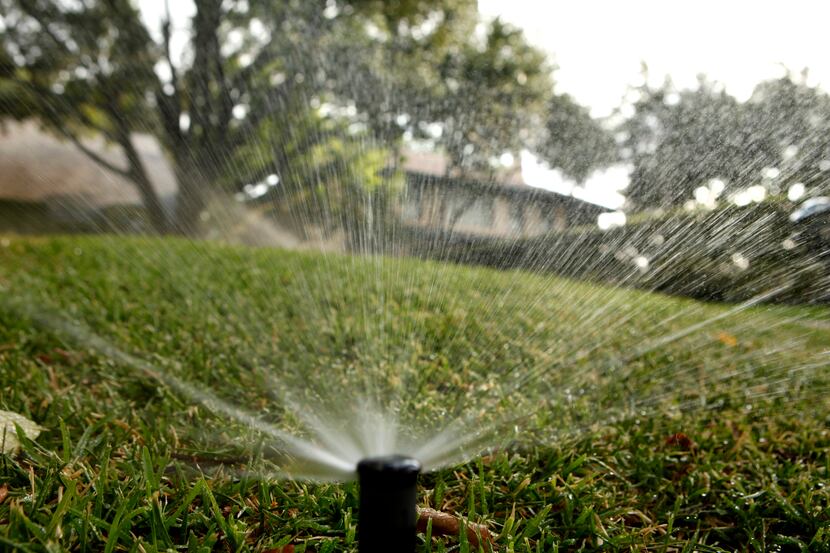 Sprinklers water the lawn in front of a house in the 3700 block of Beverly Dr. in Highland...