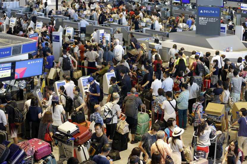 Passengers swarm the check-in counter for Delta Air Lines at Narita international airport in...