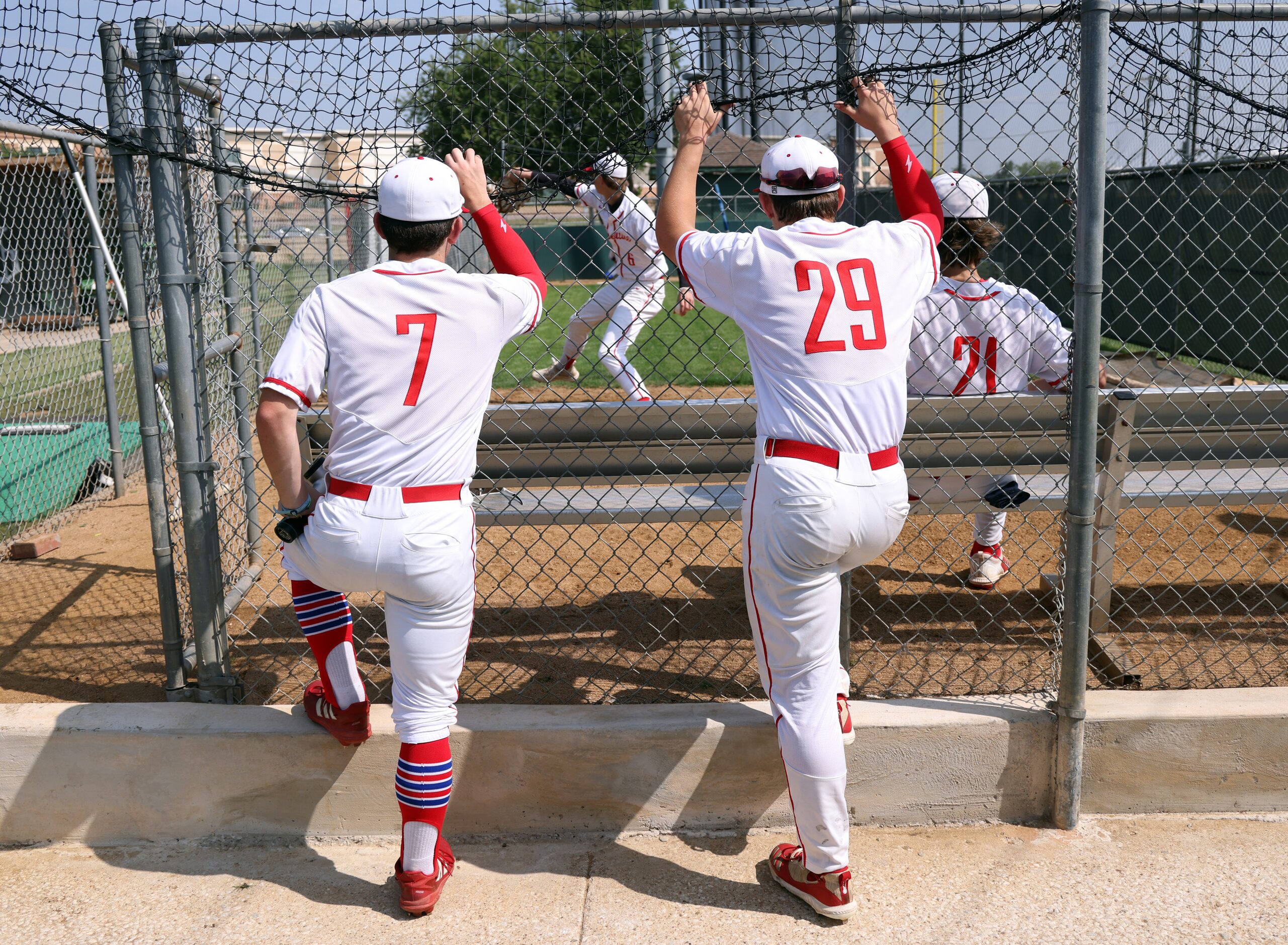 Grapevine players look on as Mustangs starting pitcher Dasan Hill (6) warms up in the...