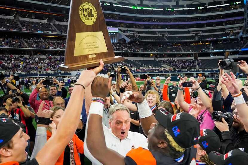 Aledo head coach Tim Buchanan lifts the championship trophy with his players as they...