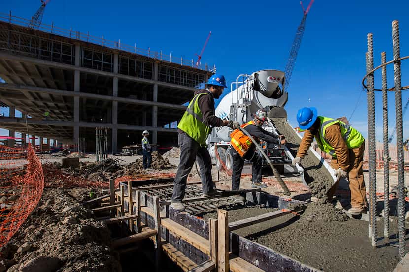 Workers pour concrete in forms during construction work at the new Toyota headquarters site...