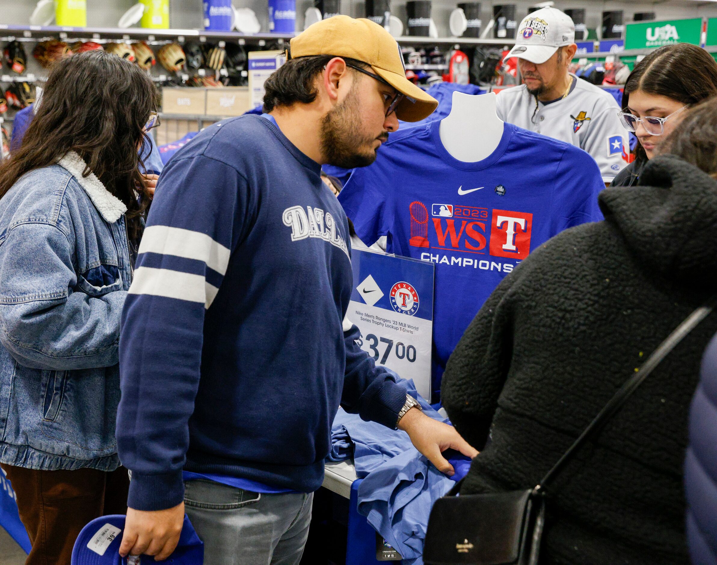 Ismael Hernandez (center) shops for Texas Rangers World Series championship shirts at an...