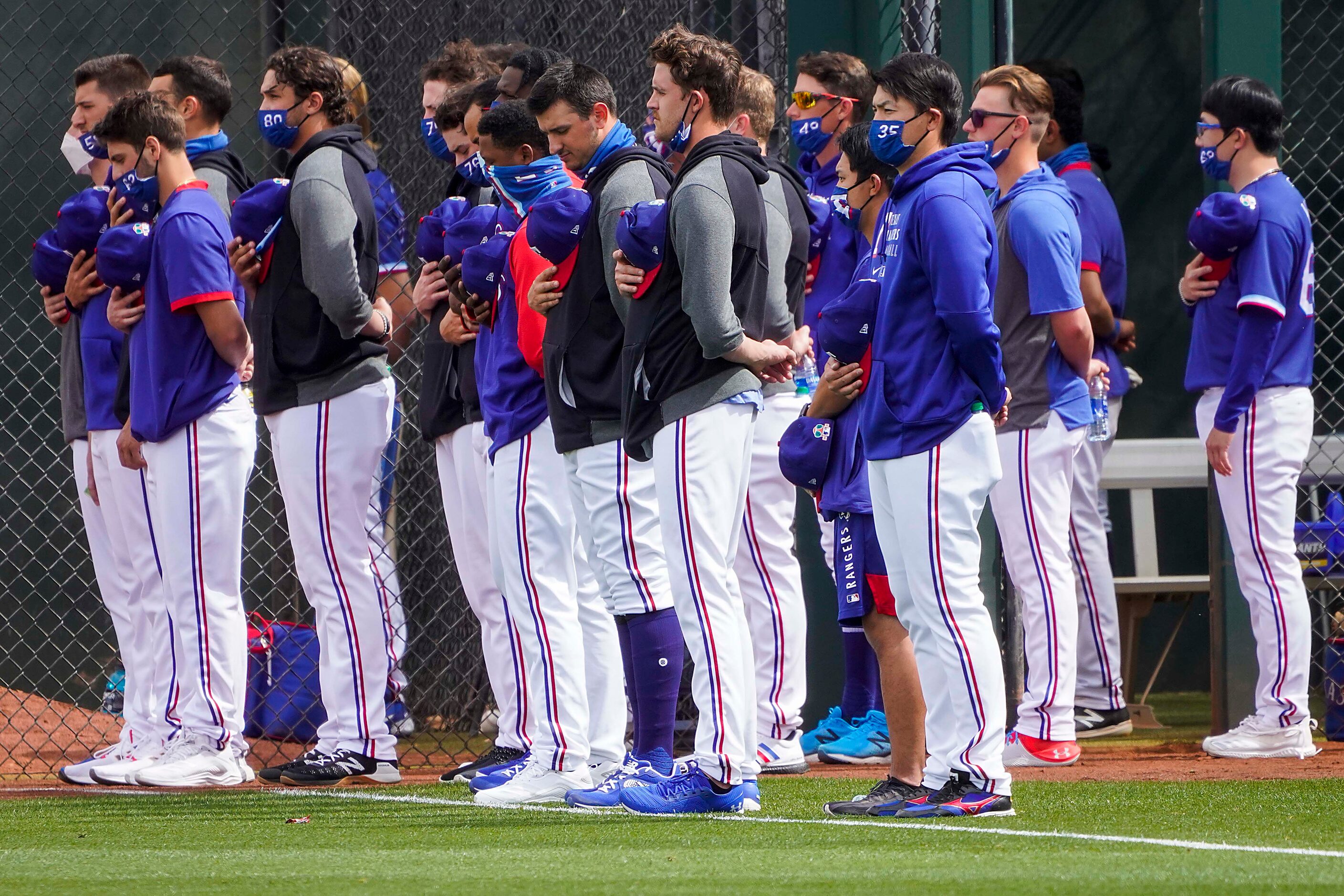 Texas Rangers players, including pitcher Kohei Arihara (35), stand for the national anthem...