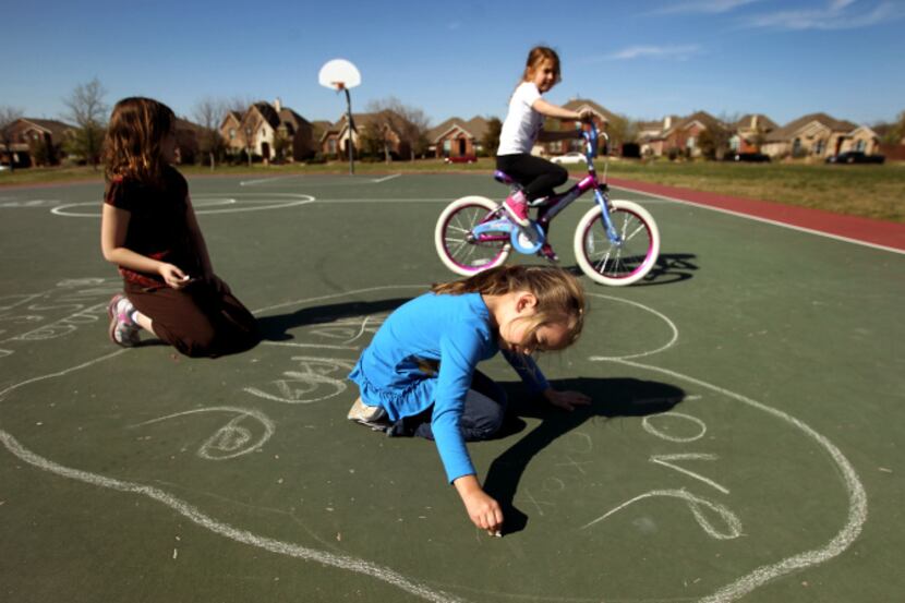 Ryan Pead, 6, (blue) makes a chalk drawing on the courts at Mourning Dove Park in Panther...