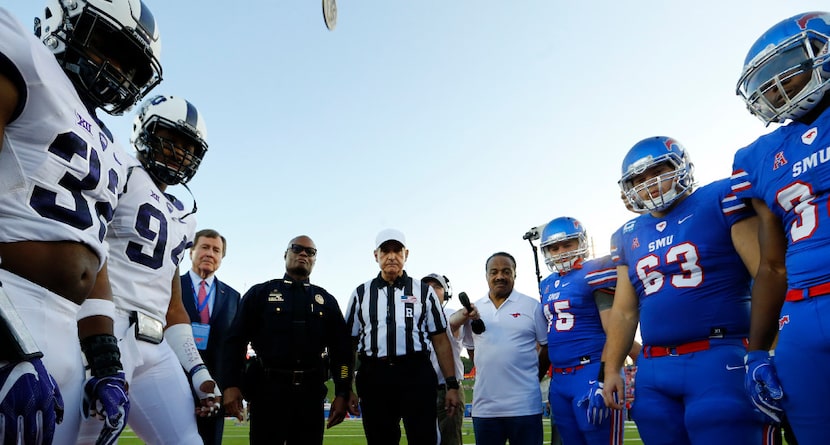 Retiring Dallas police Chief David Brown (center) watches his coin flip land as the TCU...