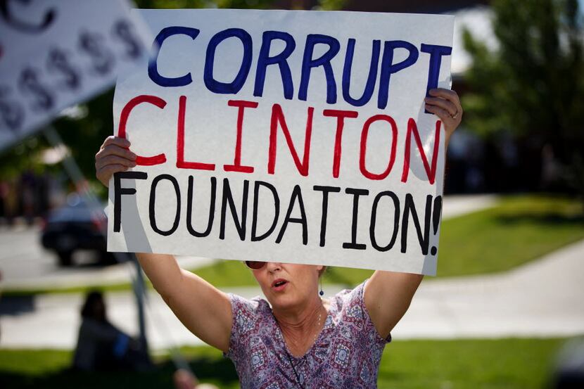A protester holds a sign reading "Corrupt Clinton Foundation" before a campaign event with...