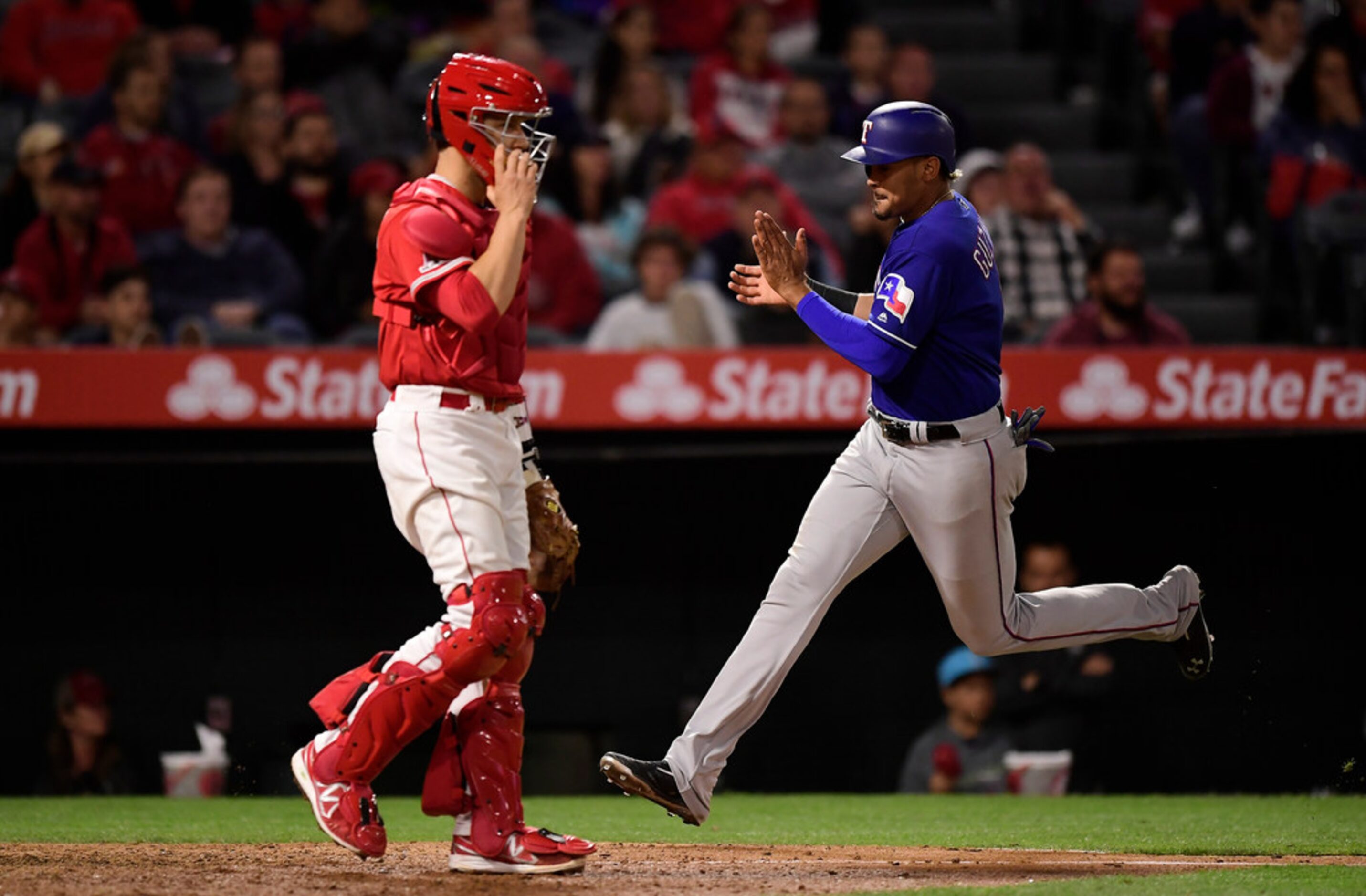 Texas Rangers' Ronald Guzman, right, scores on a single by Rougned Odor as Los Angeles...