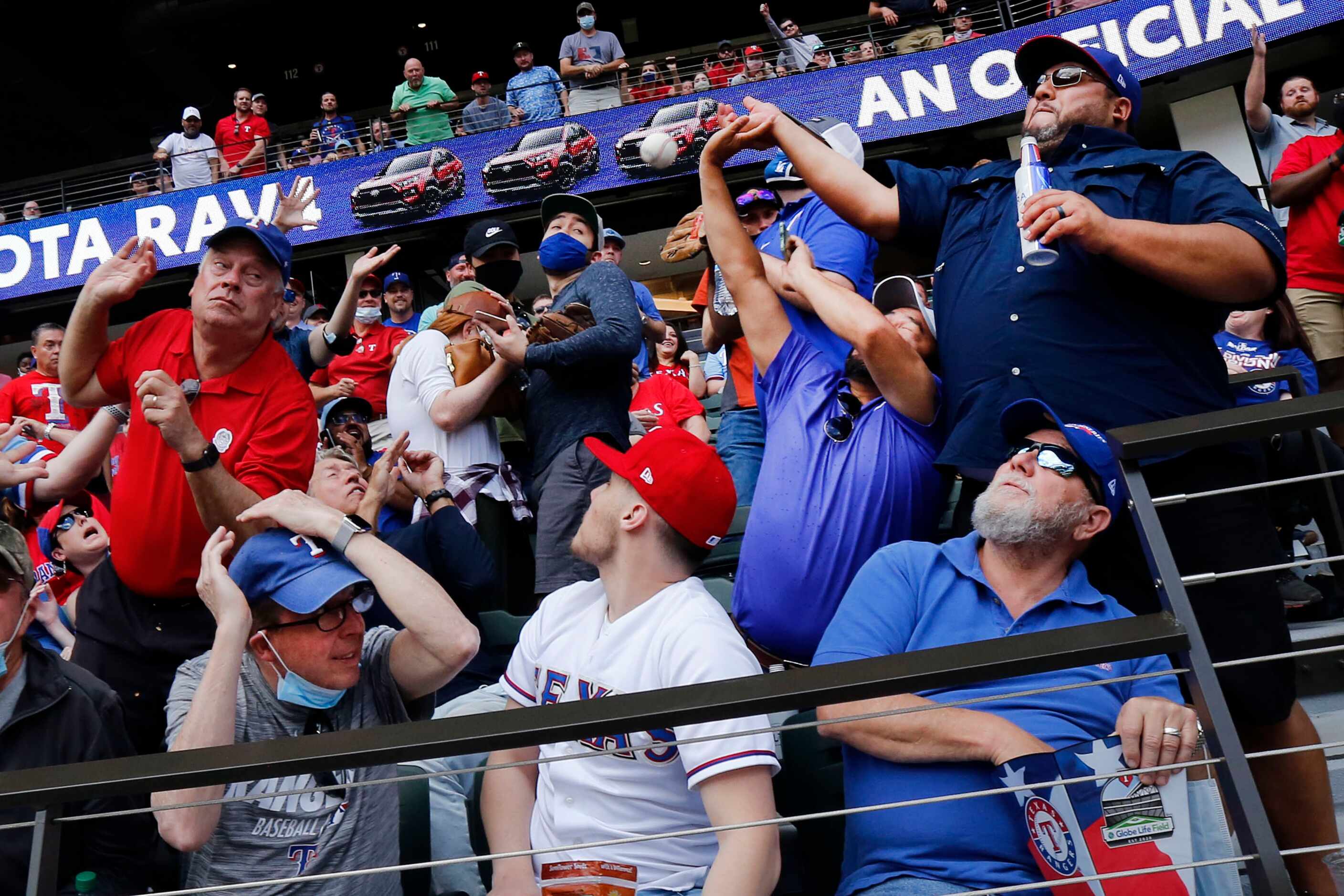 Texas Rangers fans Adam Ramirez (right) and Tommy Munoz (second from right) try to catch a...