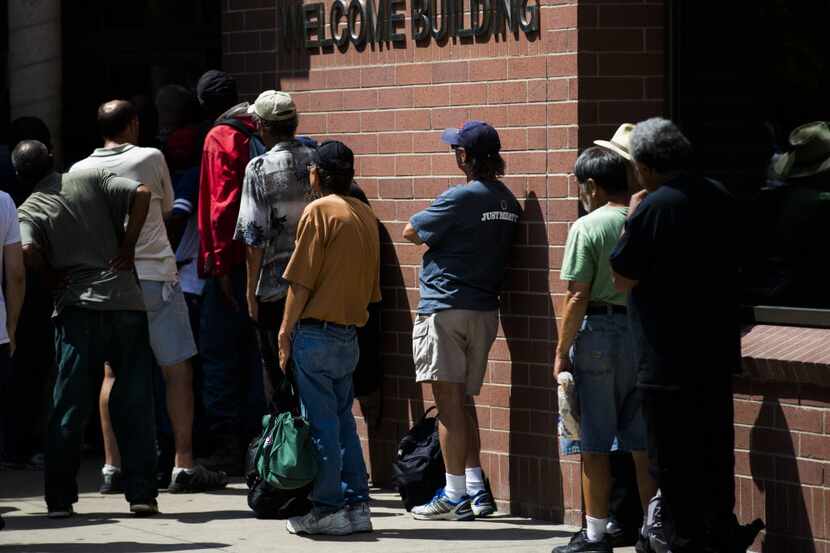 People wait in line at The Bridge Homeless Recovery Center on Corsicana Street in downtown...