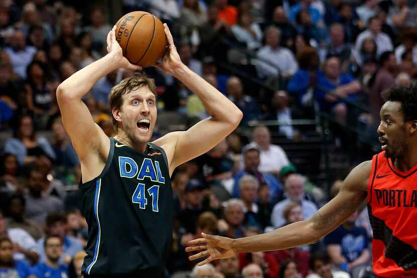 The Dallas Mavericks' Dirk Nowitzki (41) looks up to pass the ball as he's defended by the...